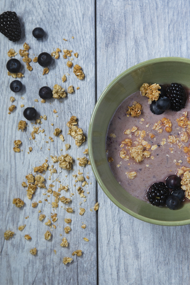 ﻿Bowl of yogurt, granola, and blueberries displayed on wooden table